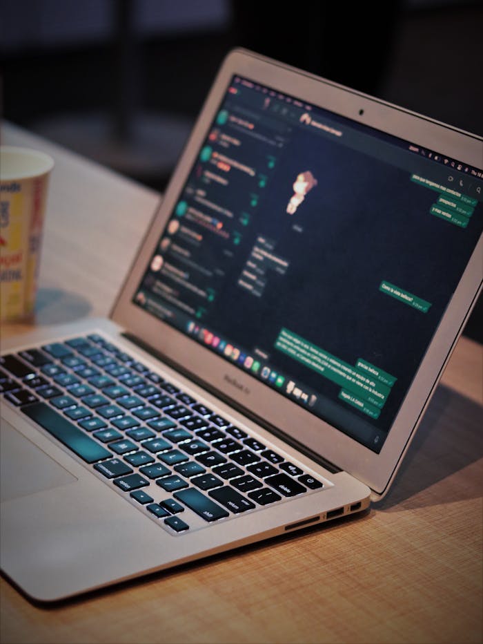 Open laptop displaying a messaging app on a wooden desk, capturing a modern workspace setting.