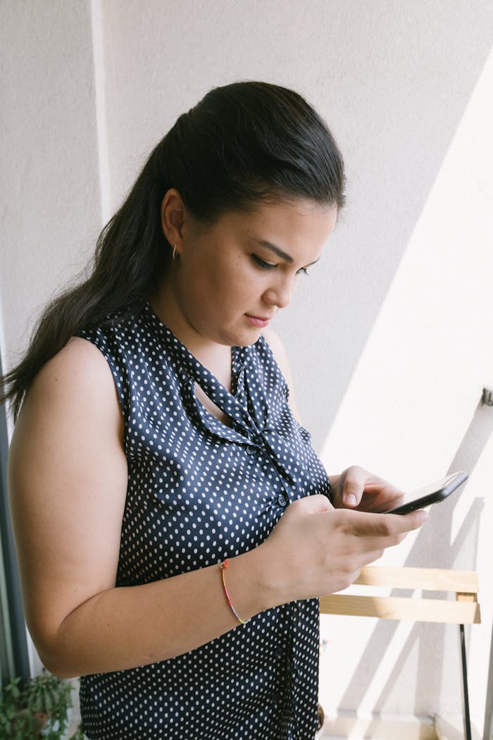 Side view of a woman using a smartphone indoors near sunlight in Istanbul, Turkey.